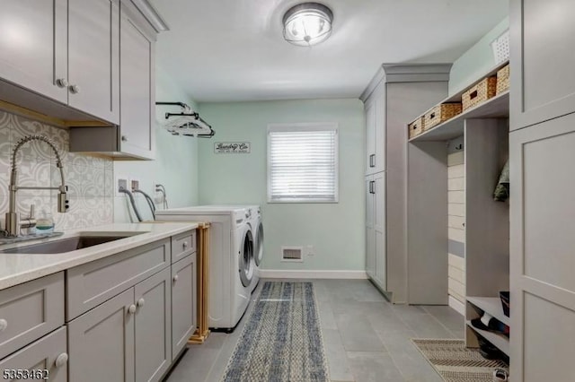 washroom featuring visible vents, washer and dryer, baseboards, a sink, and cabinet space