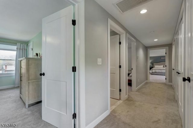 corridor featuring baseboards, light colored carpet, recessed lighting, and visible vents