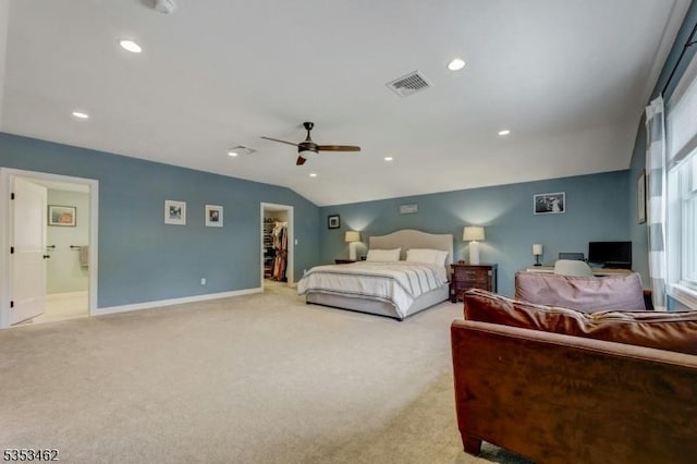 bedroom featuring visible vents, lofted ceiling, light carpet, baseboards, and a walk in closet