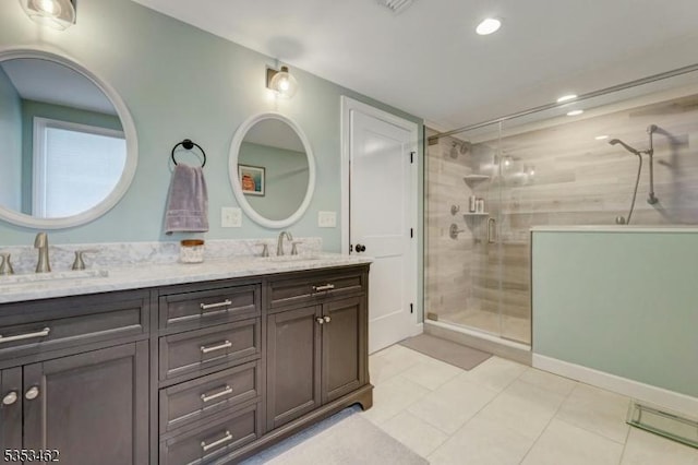 full bathroom with double vanity, a sink, and a stall shower