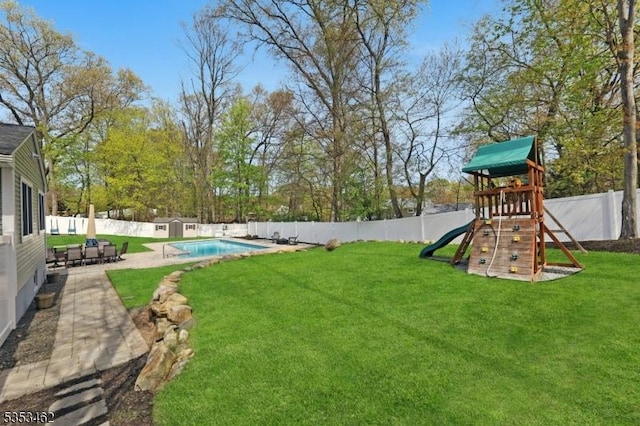 view of yard with a patio, a fenced backyard, a shed, a fenced in pool, and a playground