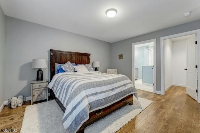 bedroom featuring baseboards, ensuite bathroom, and light wood-style floors