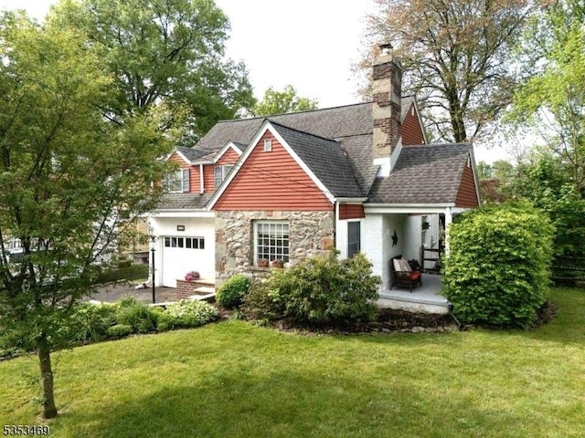 view of front of home featuring a front lawn, a chimney, stone siding, and an attached garage