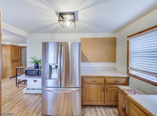 kitchen with brown cabinetry, light wood-style floors, light countertops, and appliances with stainless steel finishes