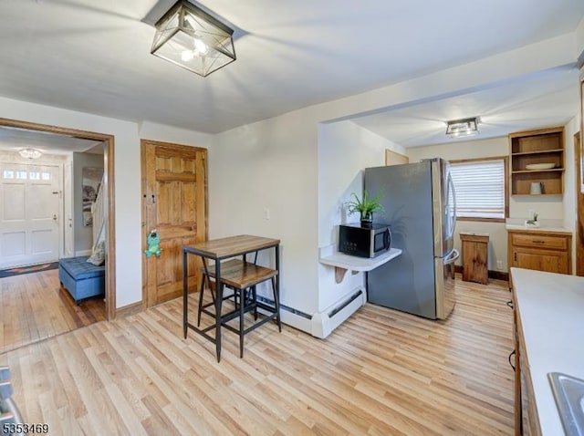 interior space with open shelves, light wood-type flooring, stainless steel appliances, and baseboards