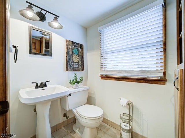 half bathroom featuring toilet, tile patterned flooring, and baseboards