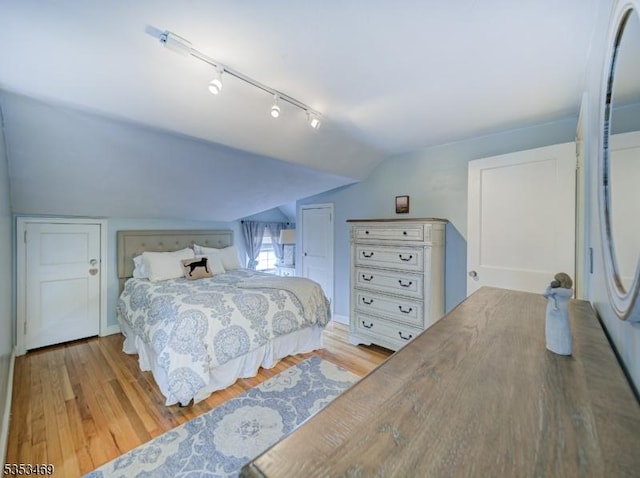 bedroom with lofted ceiling, track lighting, and wood finished floors