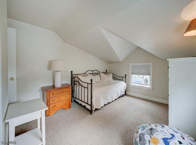 bedroom featuring baseboards, light carpet, and vaulted ceiling