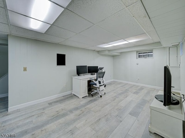 home office with light wood-style flooring, baseboards, and a drop ceiling
