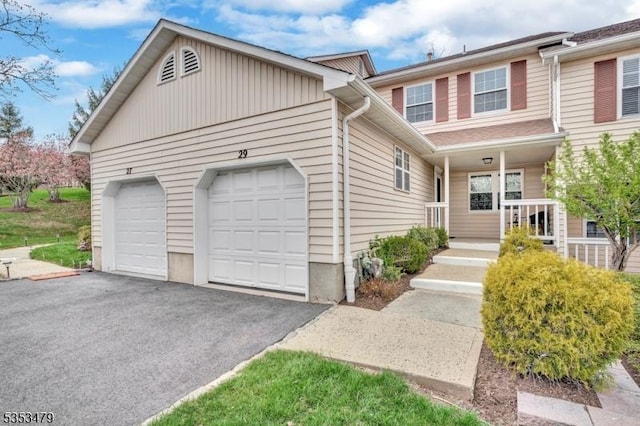 multi unit property featuring covered porch, aphalt driveway, and a garage