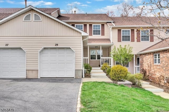 view of property with covered porch, aphalt driveway, a shingled roof, and an attached garage
