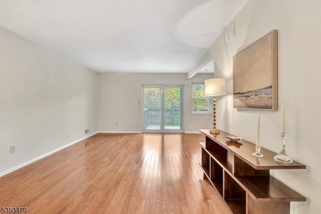 living room featuring visible vents, light wood finished floors, and baseboards