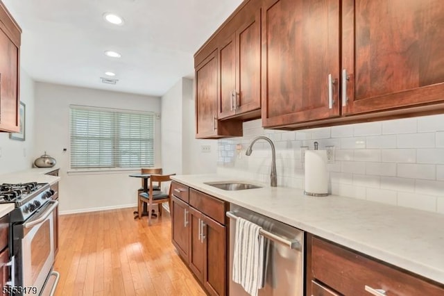 kitchen with a sink, tasteful backsplash, visible vents, light countertops, and appliances with stainless steel finishes