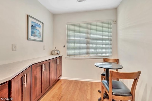 dining room with light wood finished floors, visible vents, and baseboards