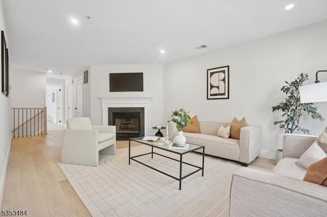 living room featuring recessed lighting, visible vents, a fireplace, and light wood-type flooring