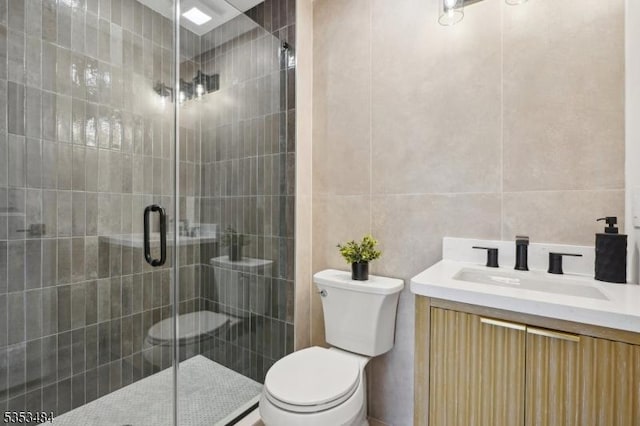 bathroom with vanity, tile walls, a stall shower, and toilet
