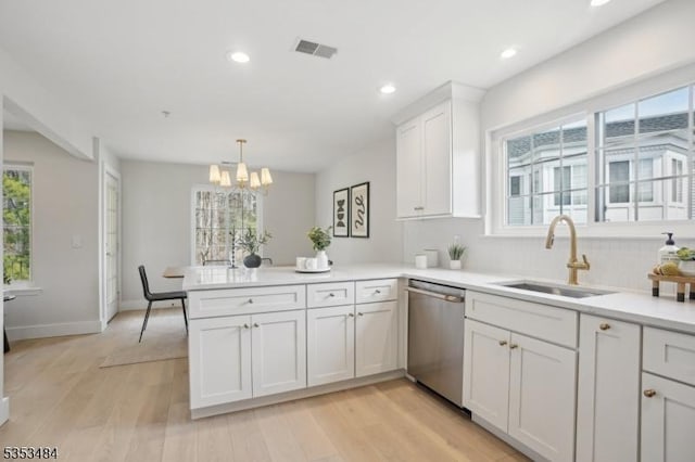 kitchen with a notable chandelier, a sink, dishwasher, light countertops, and a peninsula