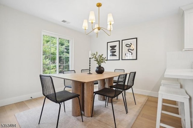 dining space with an inviting chandelier, baseboards, light wood-type flooring, and visible vents