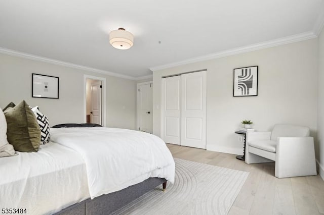 bedroom featuring crown molding, baseboards, a closet, and light wood-style flooring