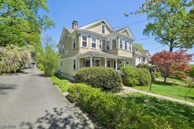 view of front of home featuring a front yard, a chimney, and covered porch