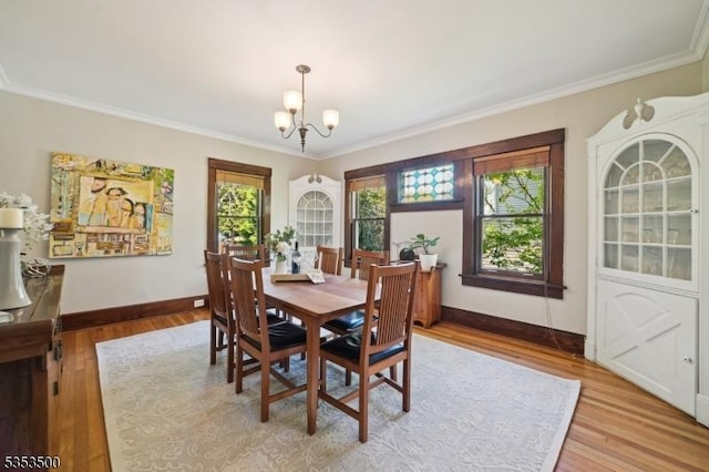 dining area with baseboards, light wood-style floors, crown molding, and a chandelier