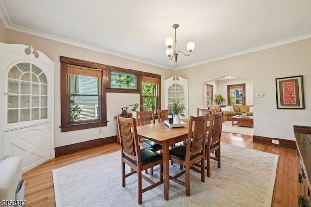 dining space featuring arched walkways, a chandelier, plenty of natural light, and ornamental molding