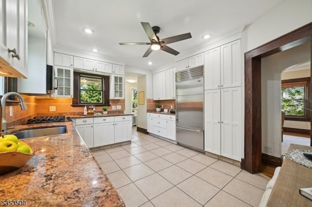 kitchen featuring white cabinets, a sink, a ceiling fan, stainless steel built in fridge, and tasteful backsplash
