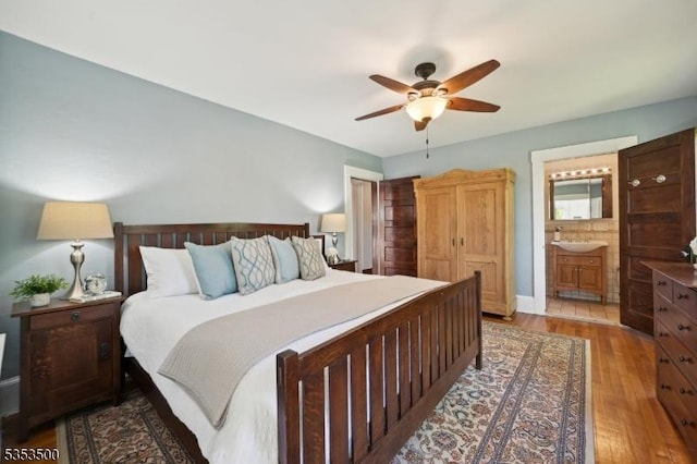 bedroom with ensuite bathroom, a sink, ceiling fan, and wood finished floors