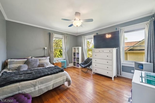 bedroom with crown molding, baseboards, ceiling fan, and light wood-type flooring
