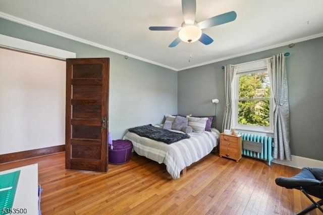 bedroom with baseboards, ornamental molding, radiator heating unit, and hardwood / wood-style floors