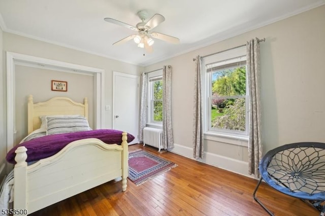 bedroom with ornamental molding, radiator, baseboards, ceiling fan, and hardwood / wood-style flooring