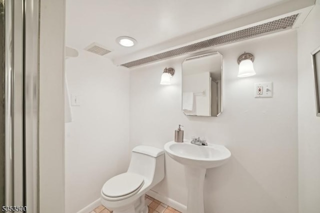 half bathroom featuring visible vents, tile patterned flooring, toilet, baseboards, and a sink