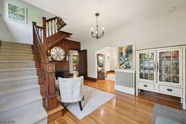 living area with arched walkways, a chandelier, light wood-style flooring, and stairway