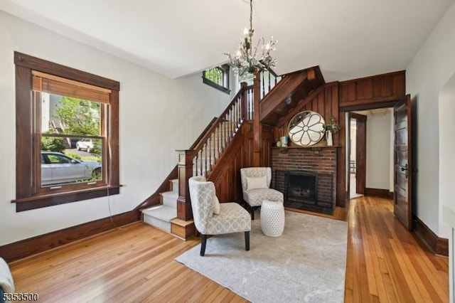 living area with baseboards, stairs, wood finished floors, and a chandelier