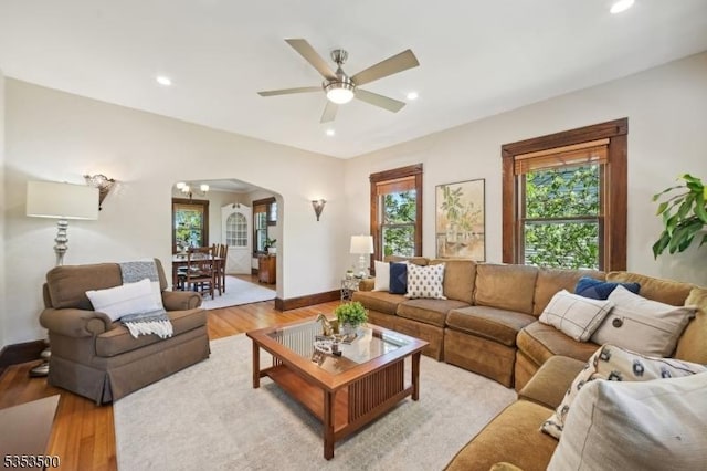 living room featuring light wood-type flooring, arched walkways, ceiling fan, and recessed lighting