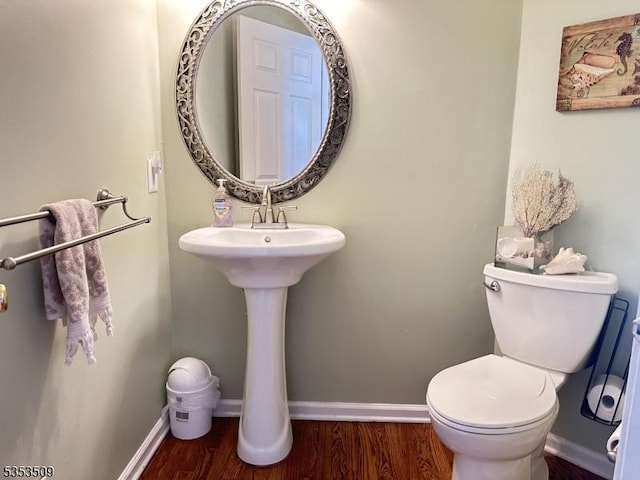 half bathroom featuring toilet, wood finished floors, and baseboards