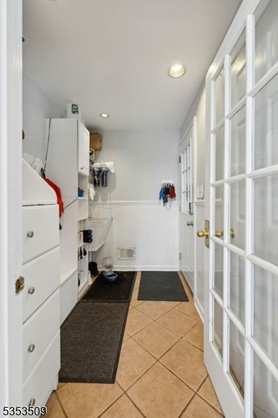 clothes washing area with light tile patterned floors, french doors, and recessed lighting