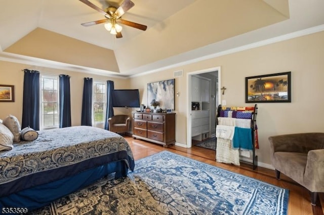 bedroom with baseboards, a raised ceiling, ceiling fan, and wood finished floors