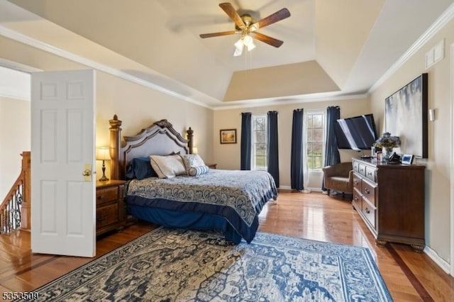 bedroom featuring a raised ceiling, ceiling fan, wood finished floors, and crown molding