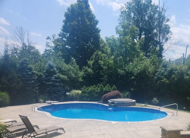 outdoor pool with a hot tub and a patio area