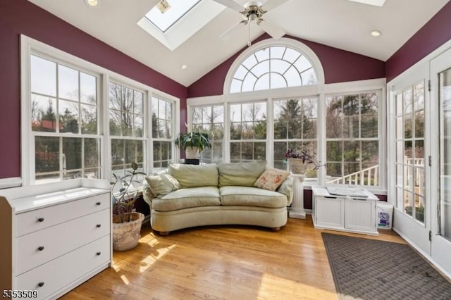 sunroom with a deck, wood finished floors, and vaulted ceiling with skylight