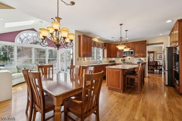 dining space with recessed lighting, an inviting chandelier, light wood-style flooring, and lofted ceiling