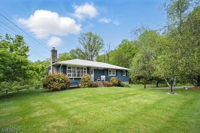 back of house featuring fence, a chimney, and a lawn
