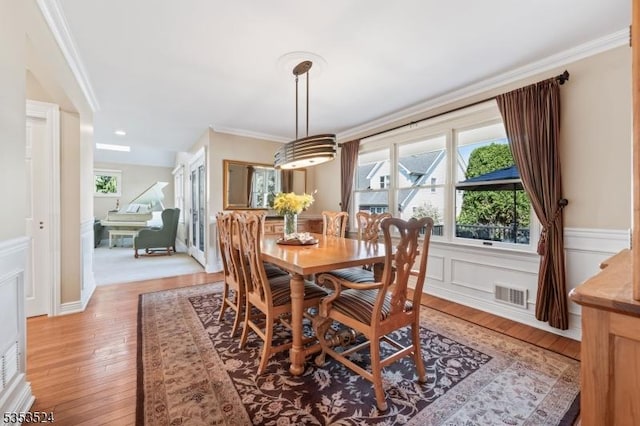 dining space featuring visible vents, light wood-style floors, and crown molding