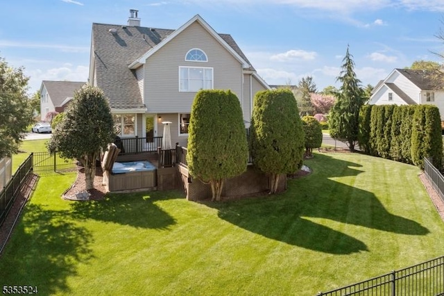 rear view of house with a fenced backyard, a hot tub, a wooden deck, and a yard