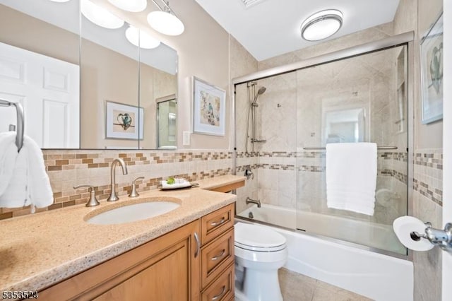 full bathroom featuring vanity, decorative backsplash, tile patterned flooring, toilet, and bath / shower combo with glass door