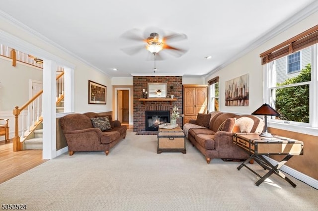 living room with crown molding, stairs, a brick fireplace, light colored carpet, and a ceiling fan