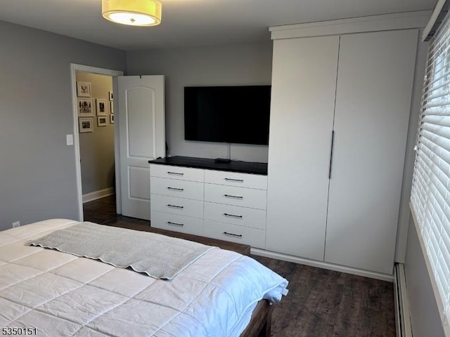 bedroom with dark wood finished floors, baseboards, and a baseboard heating unit
