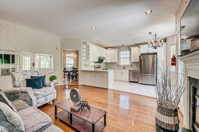 living room featuring a fireplace, recessed lighting, a notable chandelier, and light wood-type flooring