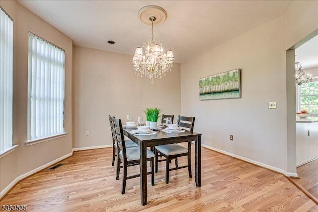dining area with light wood-style floors, baseboards, a chandelier, and visible vents